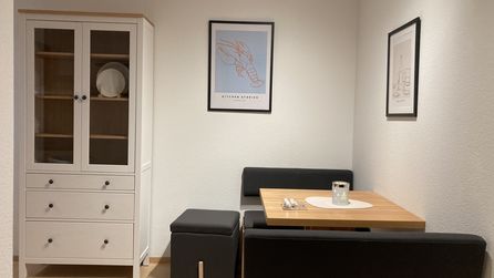Kleine Essecke mit Holztisch schwarzer Bank Vitrine und Hummerposter
