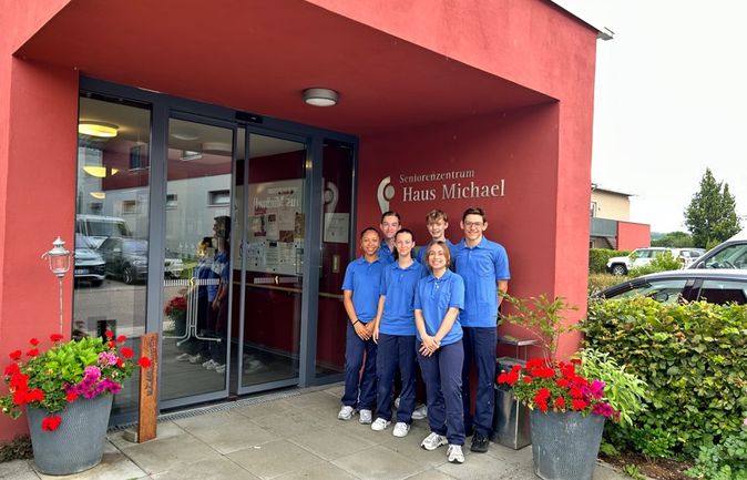 Sechs Jugendliche in blauen Poloshirts am Eingang des Seniorenzentrums Haus Michael