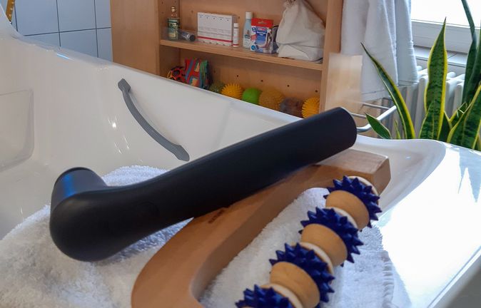 Badewannenablage mit Holzmassagerolle und blauen Noppen auf Handtuch
