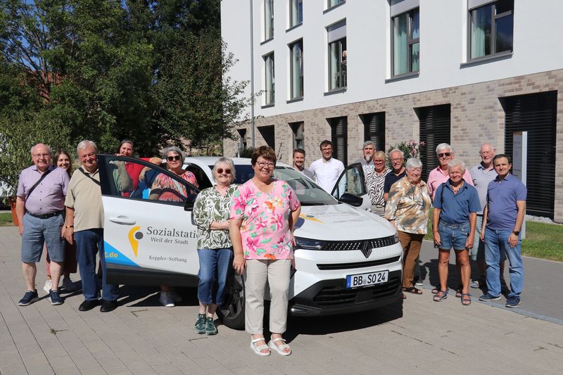 mehrere Personen stehen um ein weißes Fahrzeug mit Aufdruck der Keppler-Stiftung herum